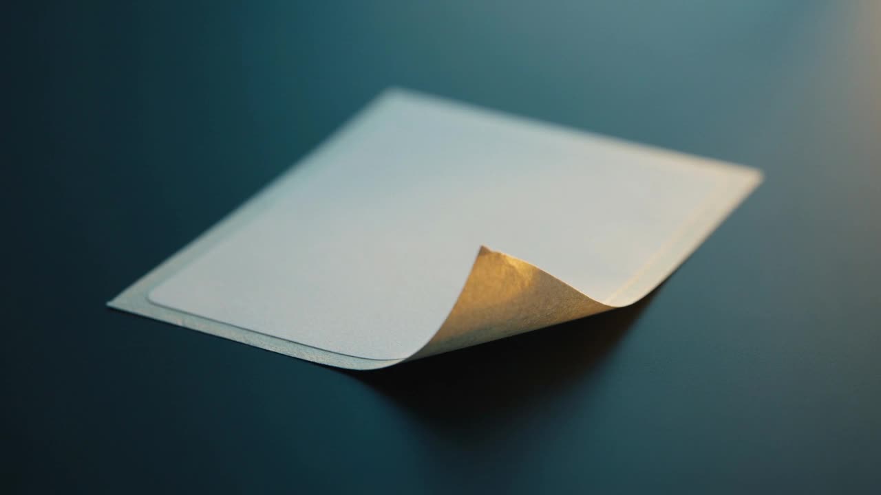 A pale paper label peeling up at one corner on a dark surface.